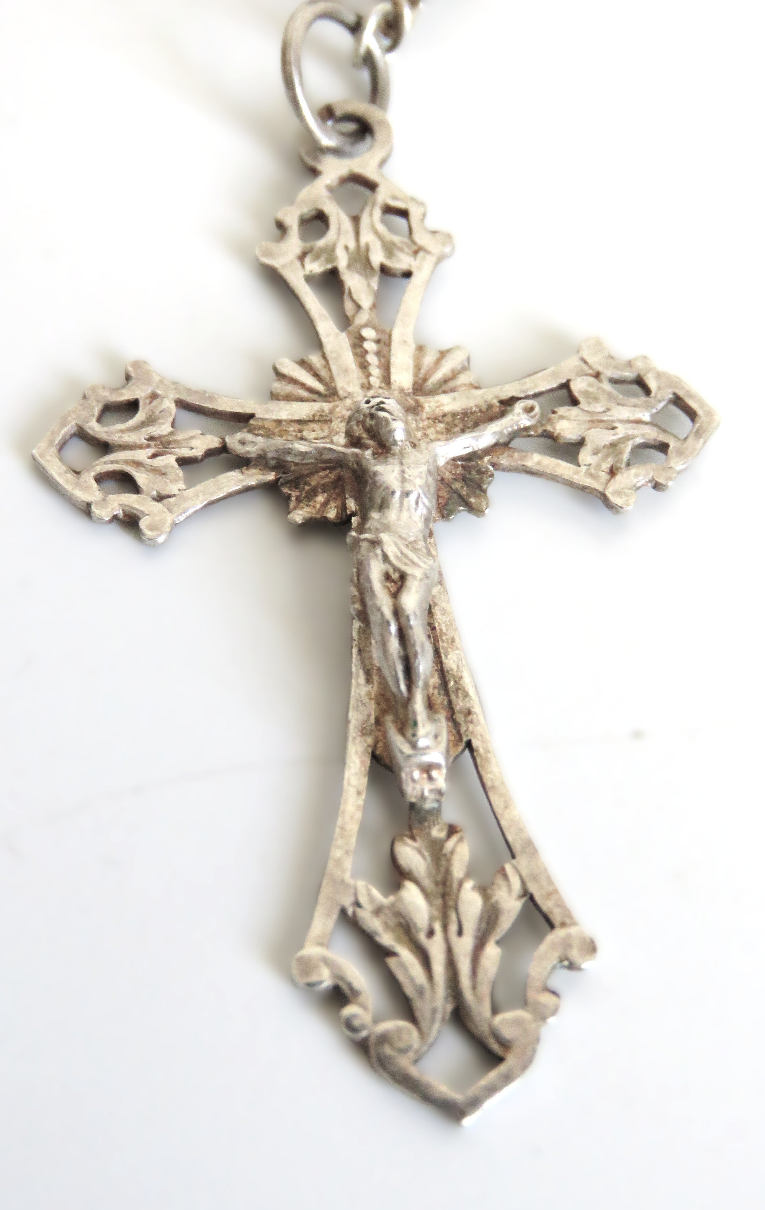 Decorative silver cross pendant on a white background