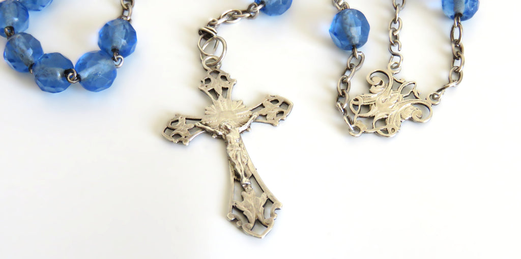 Blue rosary beads with silver cross on a white background