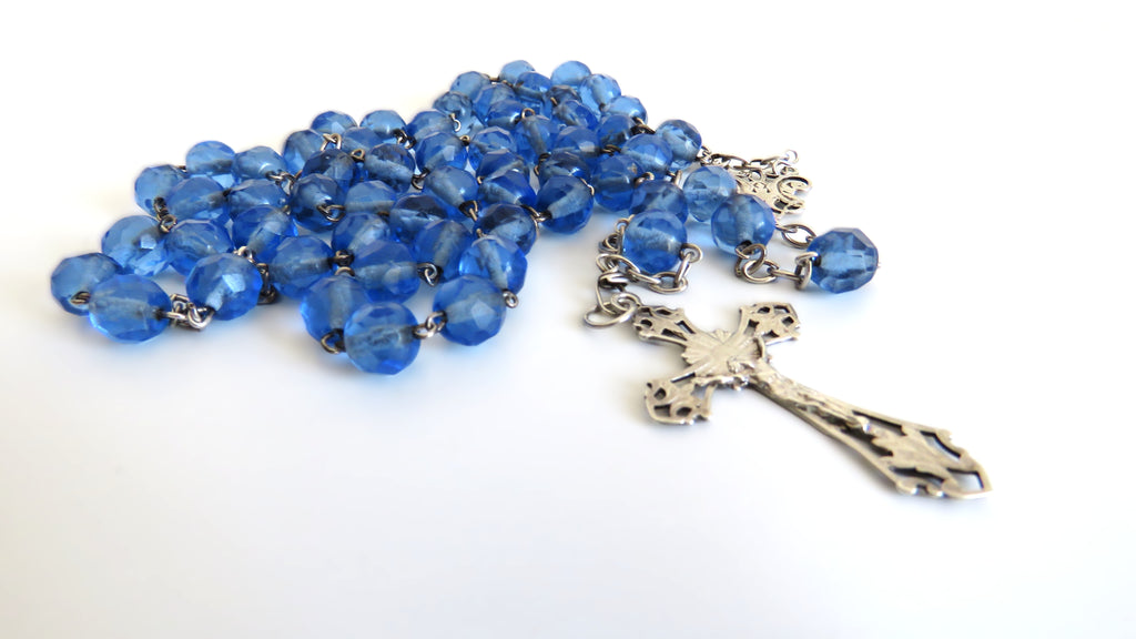 Blue rosary with a silver cross on a white background