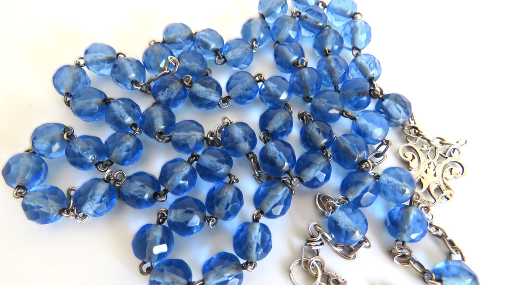 Blue rosary beads on a white background