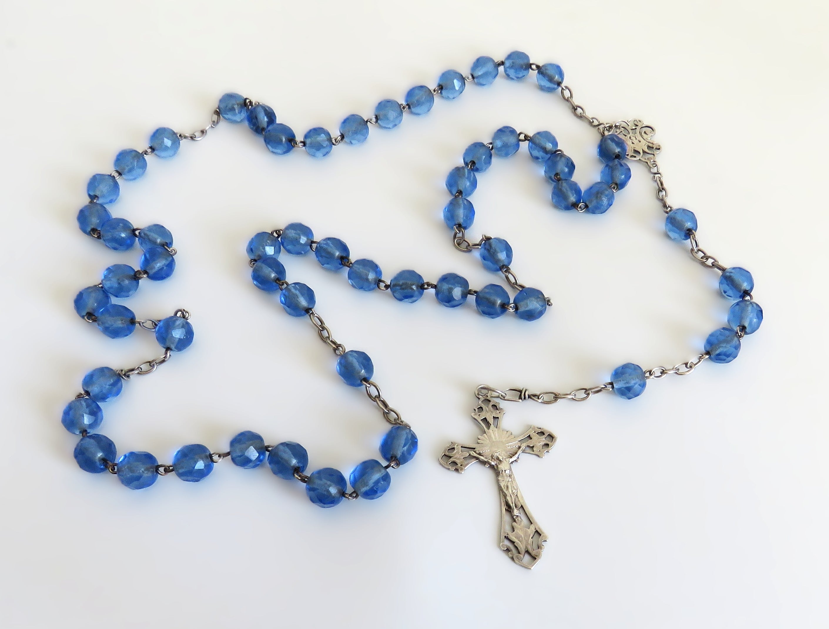 Blue rosary with a silver cross on a white background