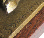 Close-up of a bronze sculpture with engraved text on a wooden base