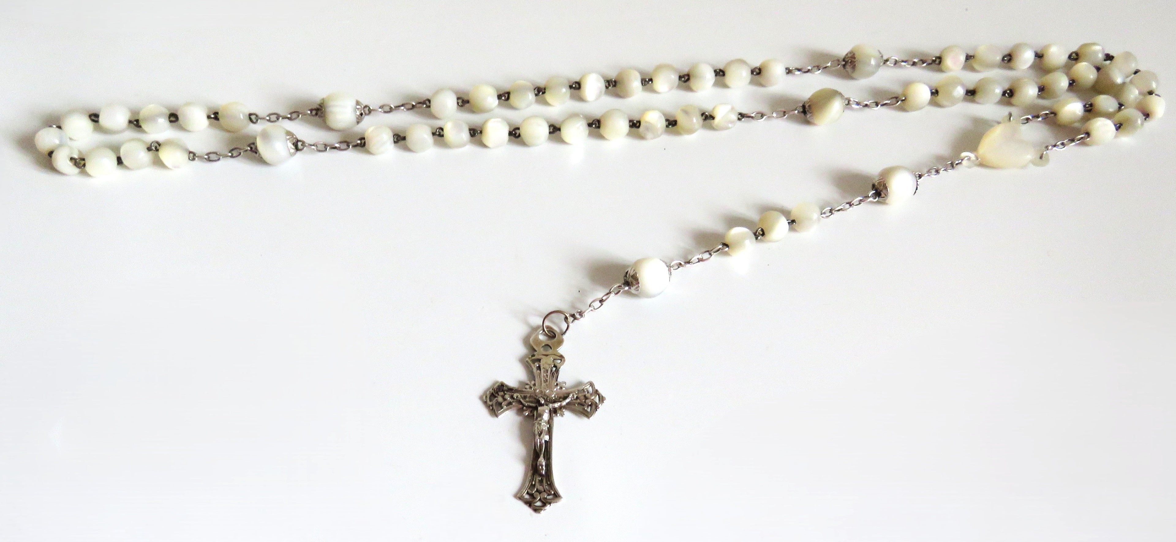 Mother of pearl rosary with silver crucifix on a wite background