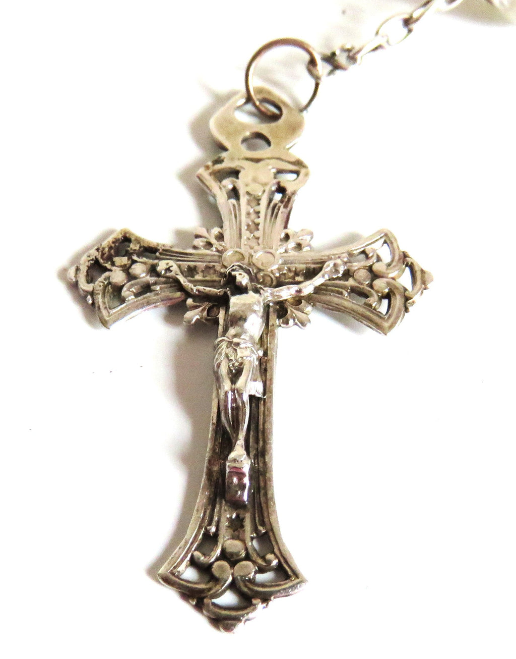Silver crucifix pendant with intricate designs on a white background