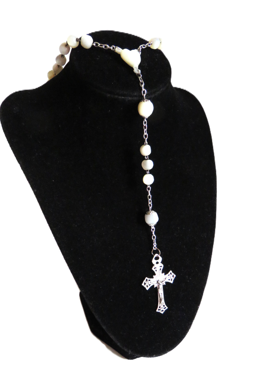 Mother of pearl rosary with silver crucifix on a dispaly stand on a  white background