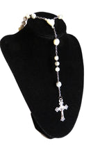 Mother of pearl rosary with silver crucifix on a dispaly stand on a  white background
