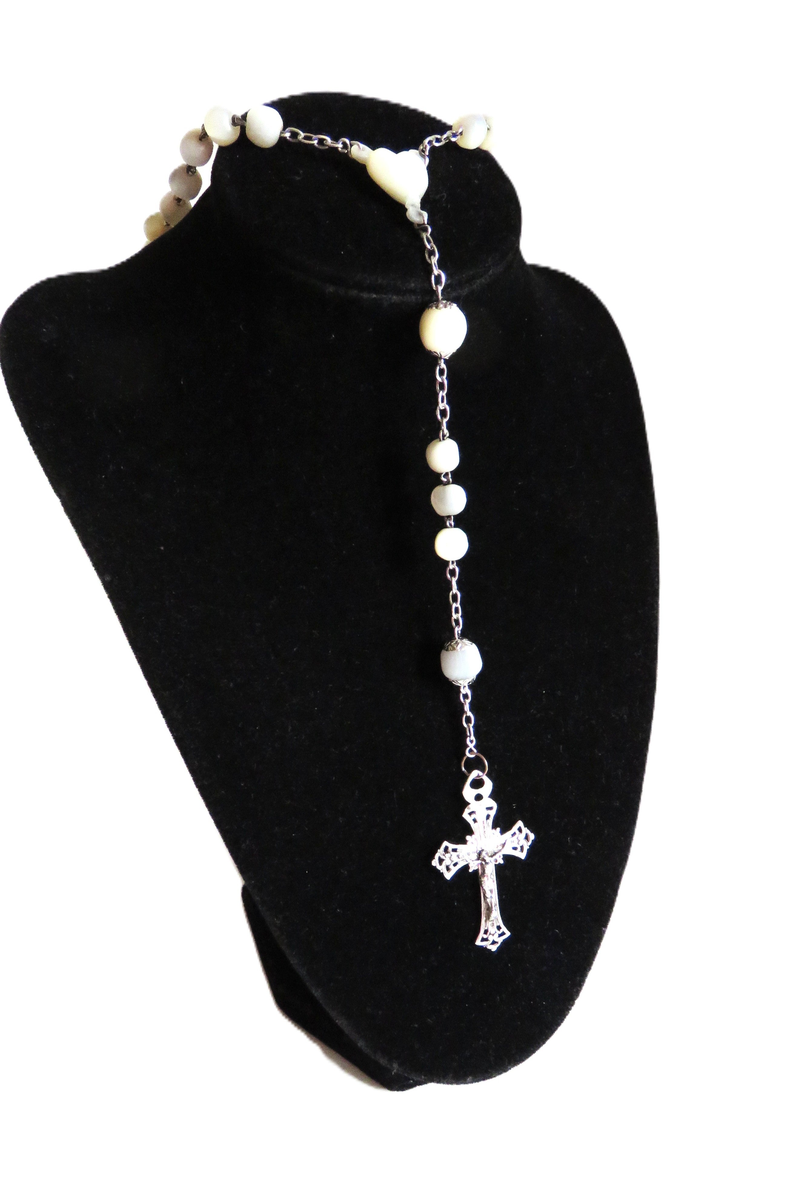 Mother of pearl rosary with silver crucifix on a dispaly stand on a  white background