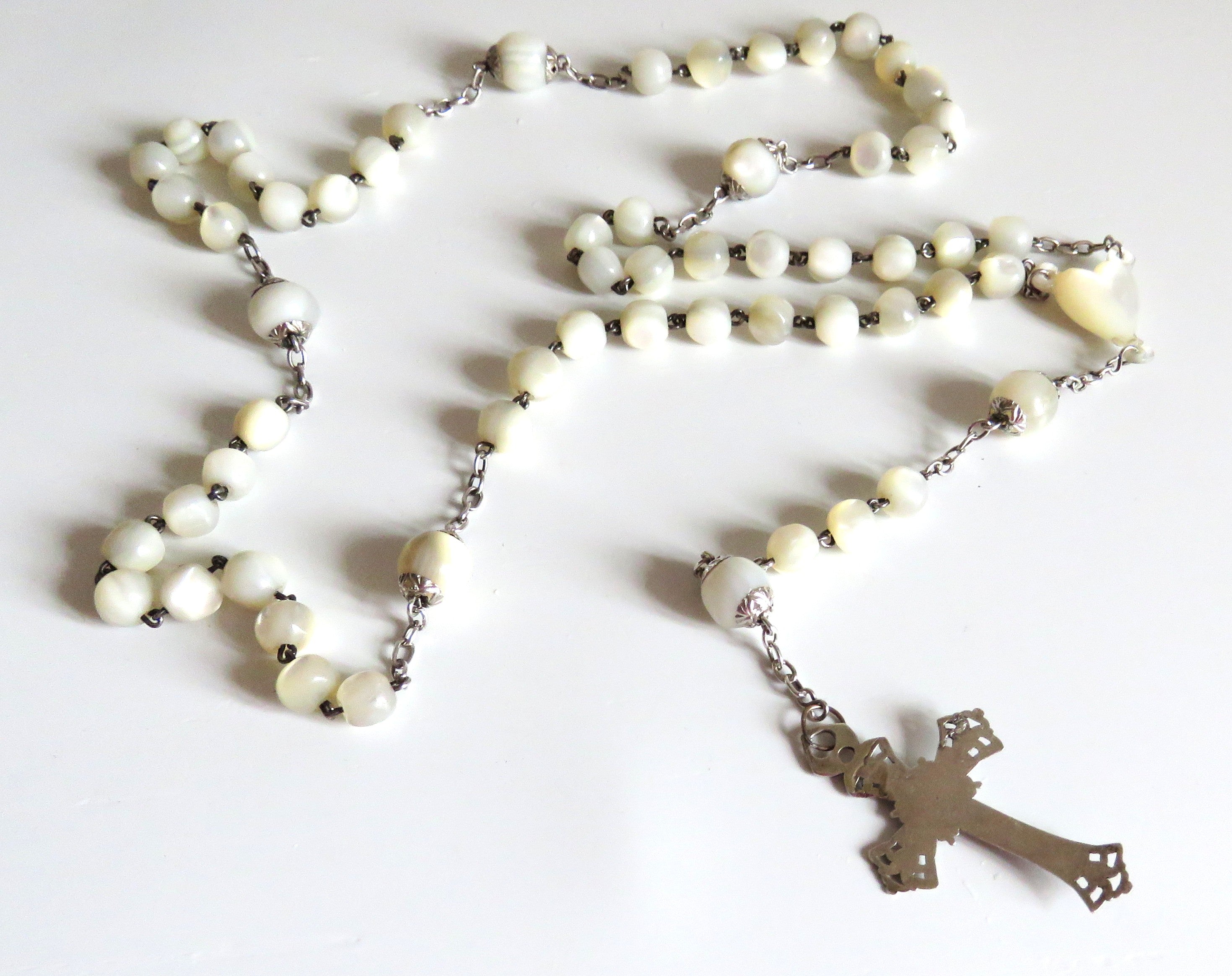 Mother of pearl rosary with silver crucifix on a wite background