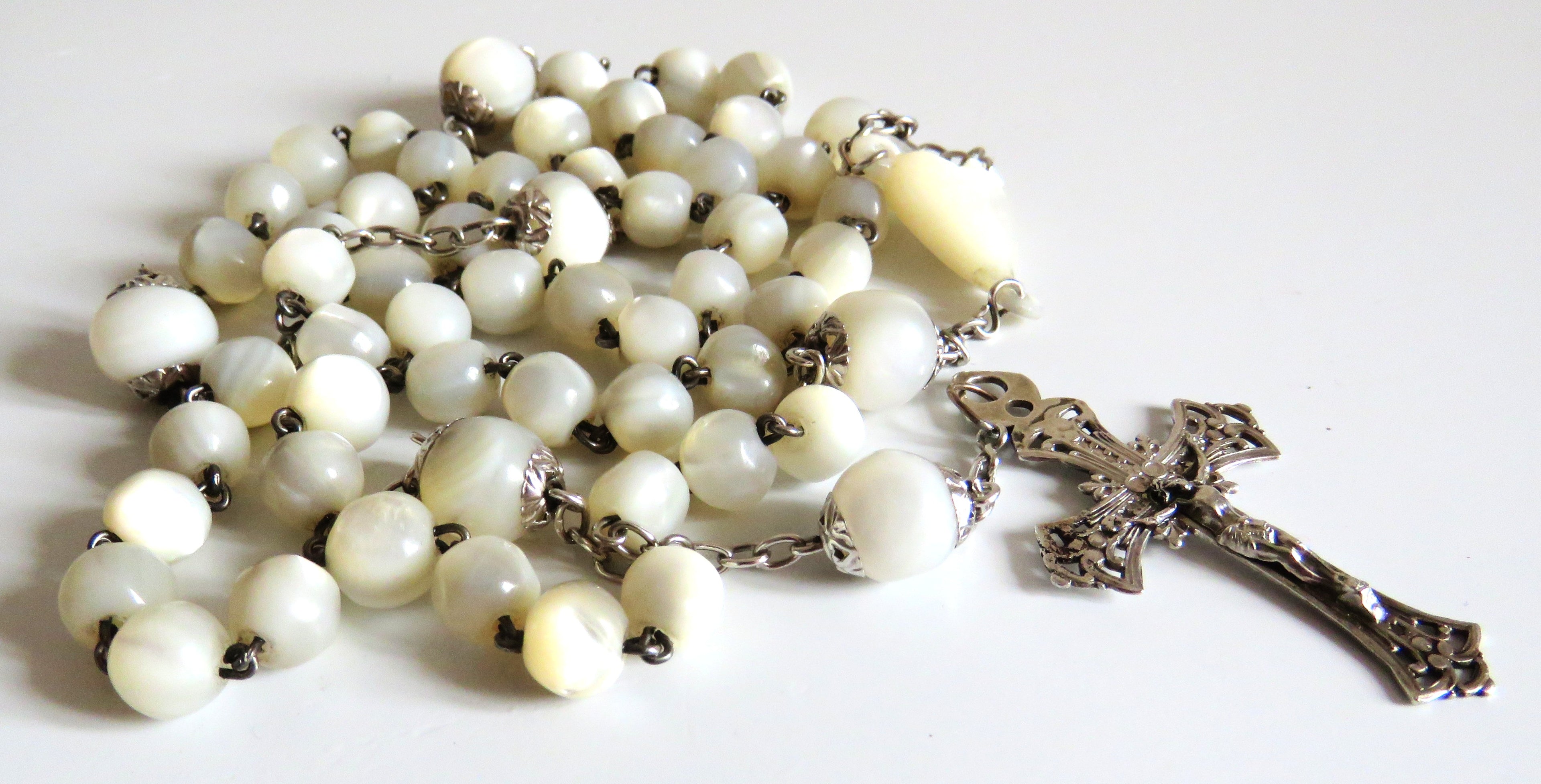 Mother of pearl rosary with silver crucifix on a wite background