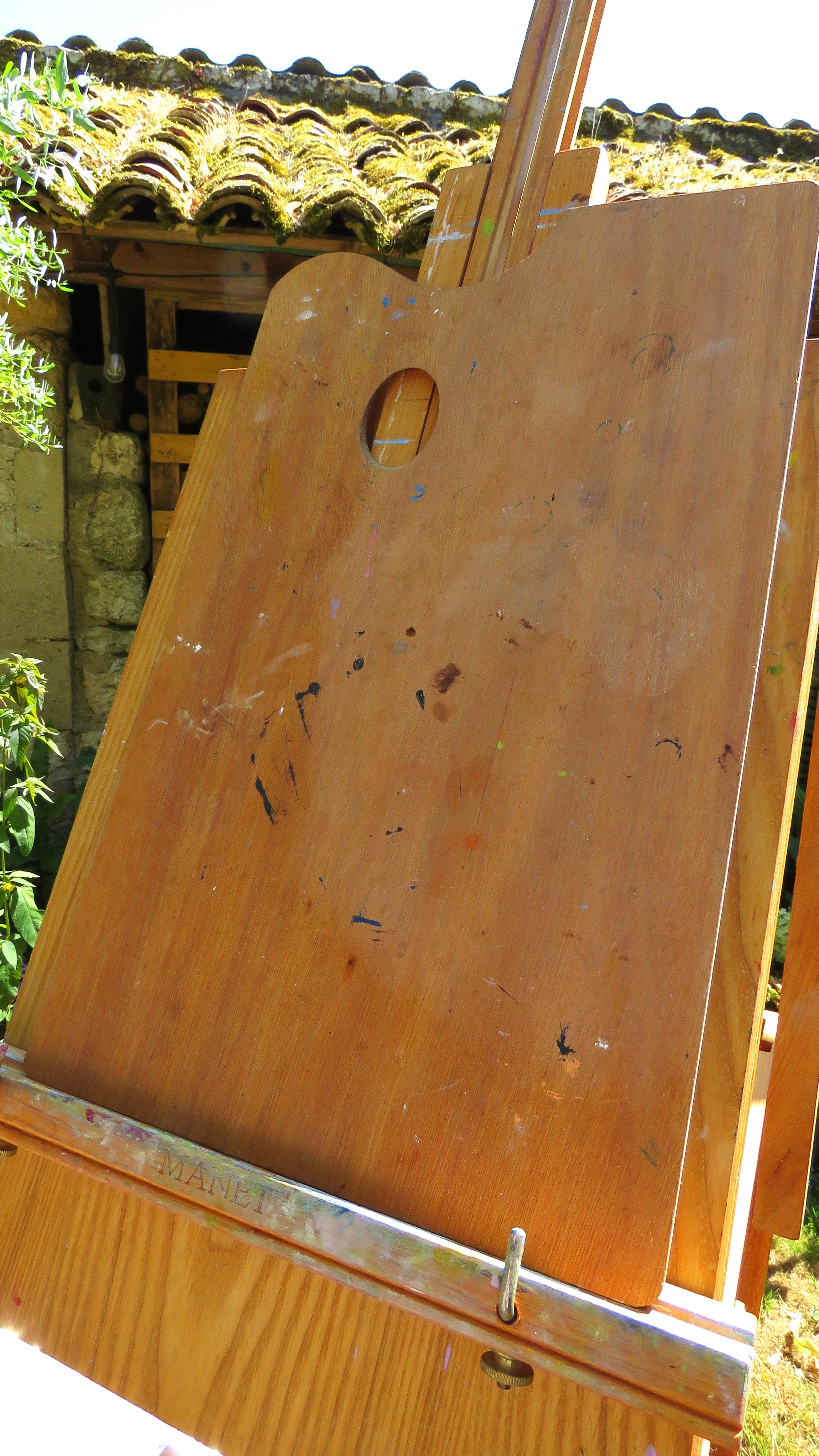 Wooden artist's easel with paint splatters outdoors