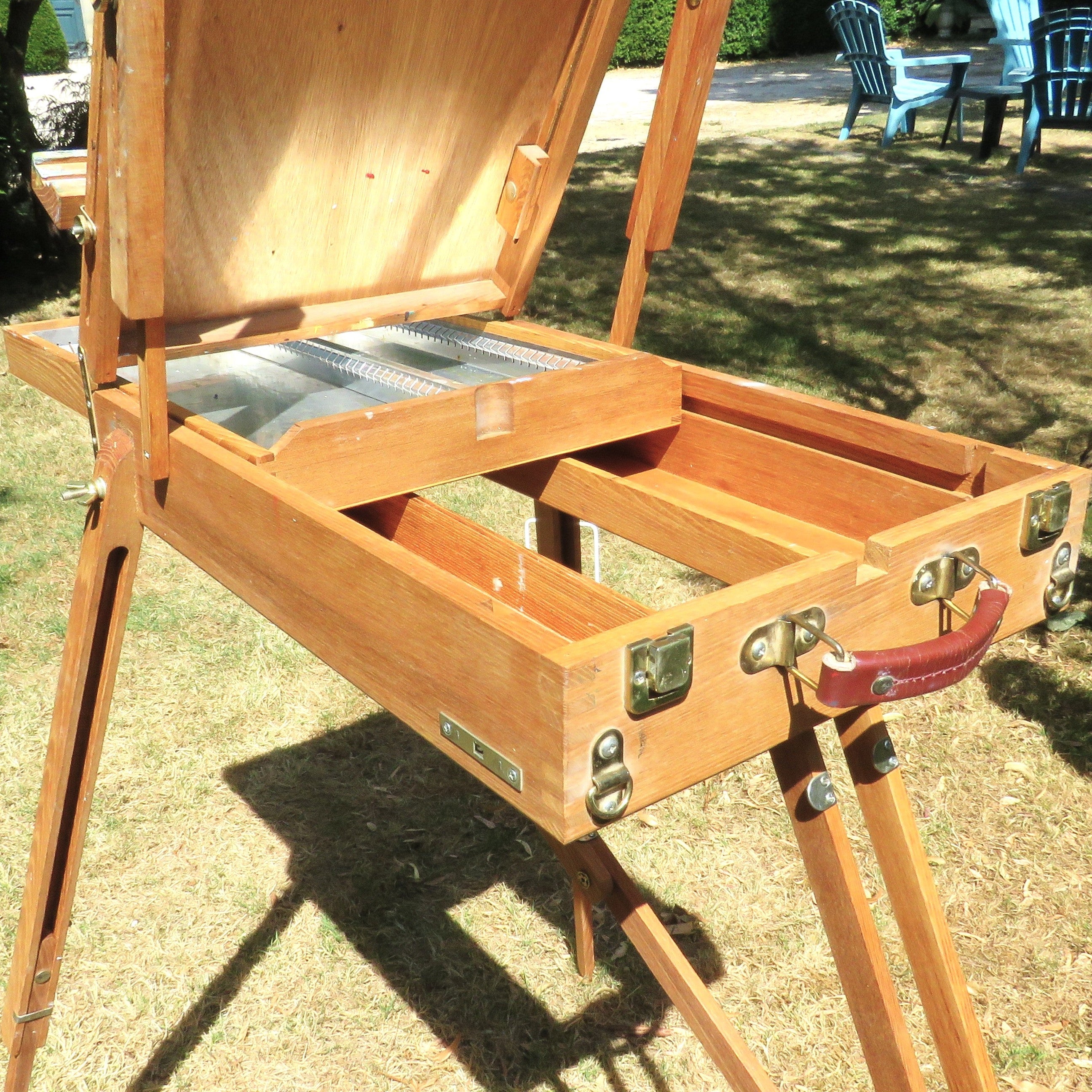 Wooden artist's easel in a garden setting with flowers 