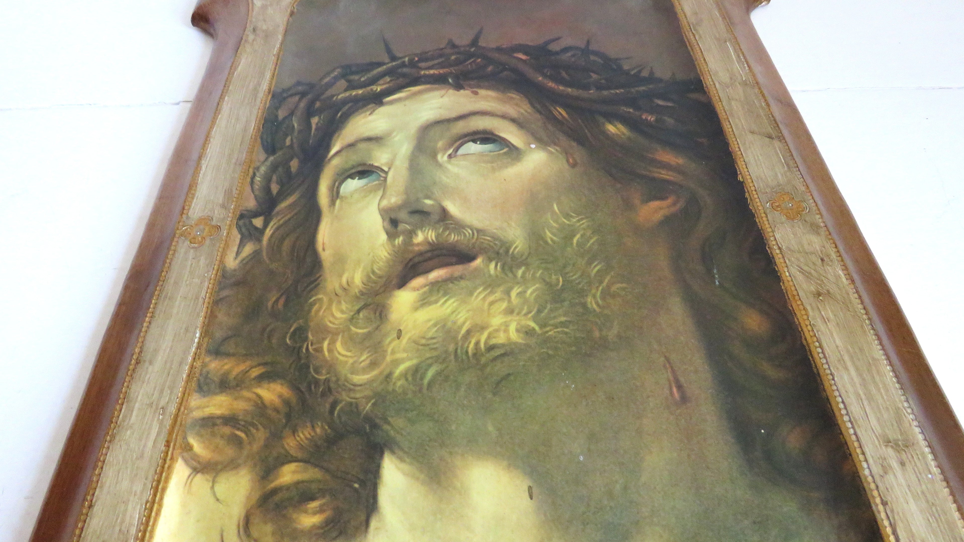 close up of a vintage portrait of a Christ with a crown of thorns in a wooden frame on a white background