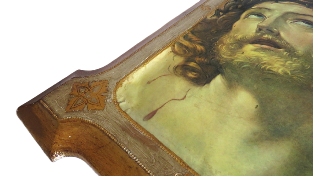 corner close up of a decorative plaque with Christ design in a gold frame on a white background