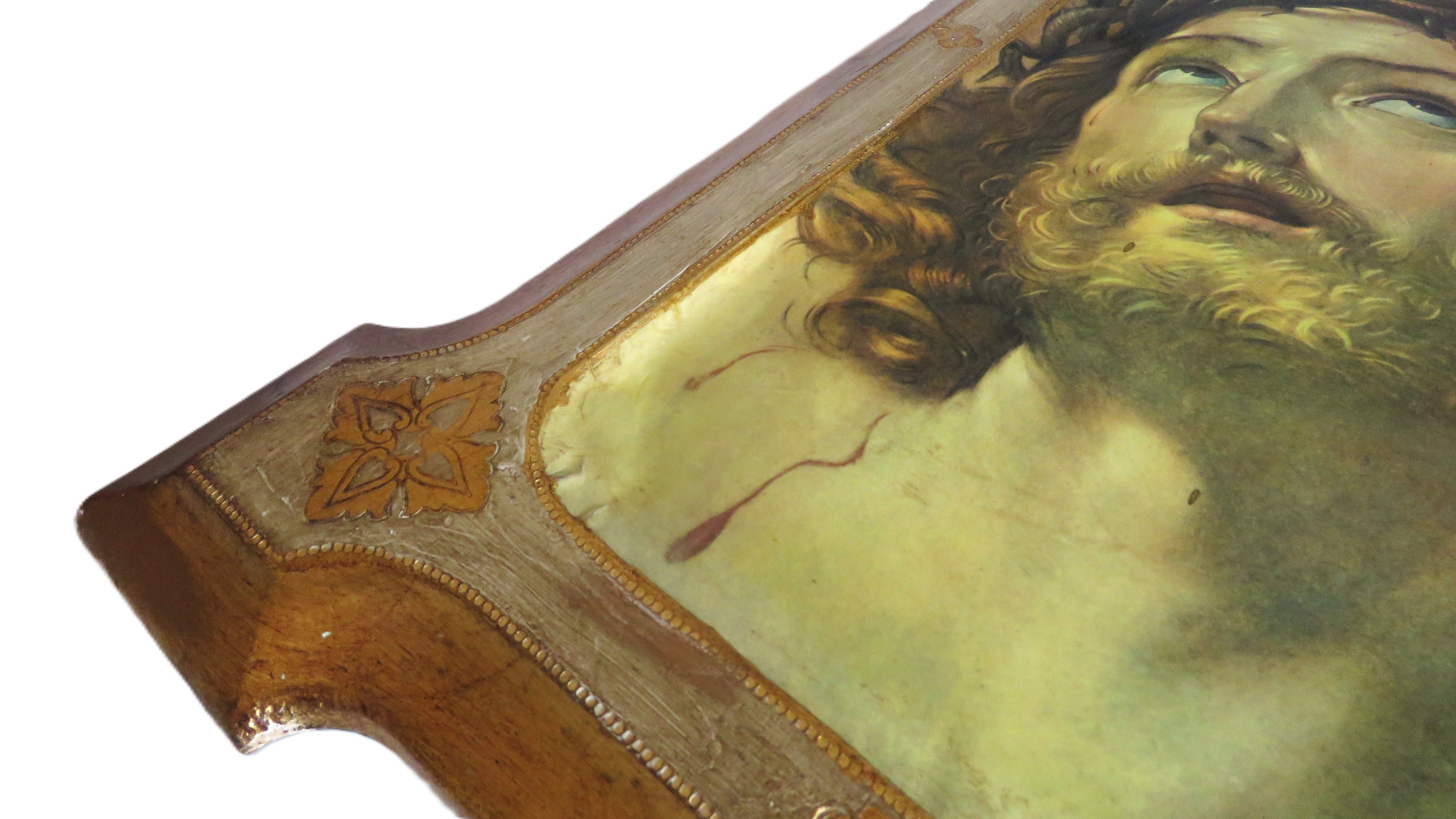 corner close up of a decorative plaque with Christ design in a gold frame on a white background