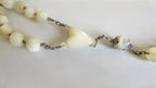 Necklace with white beads and a heart-shaped centre on a light background