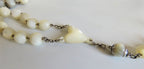 White beaded necklace on a light gray background