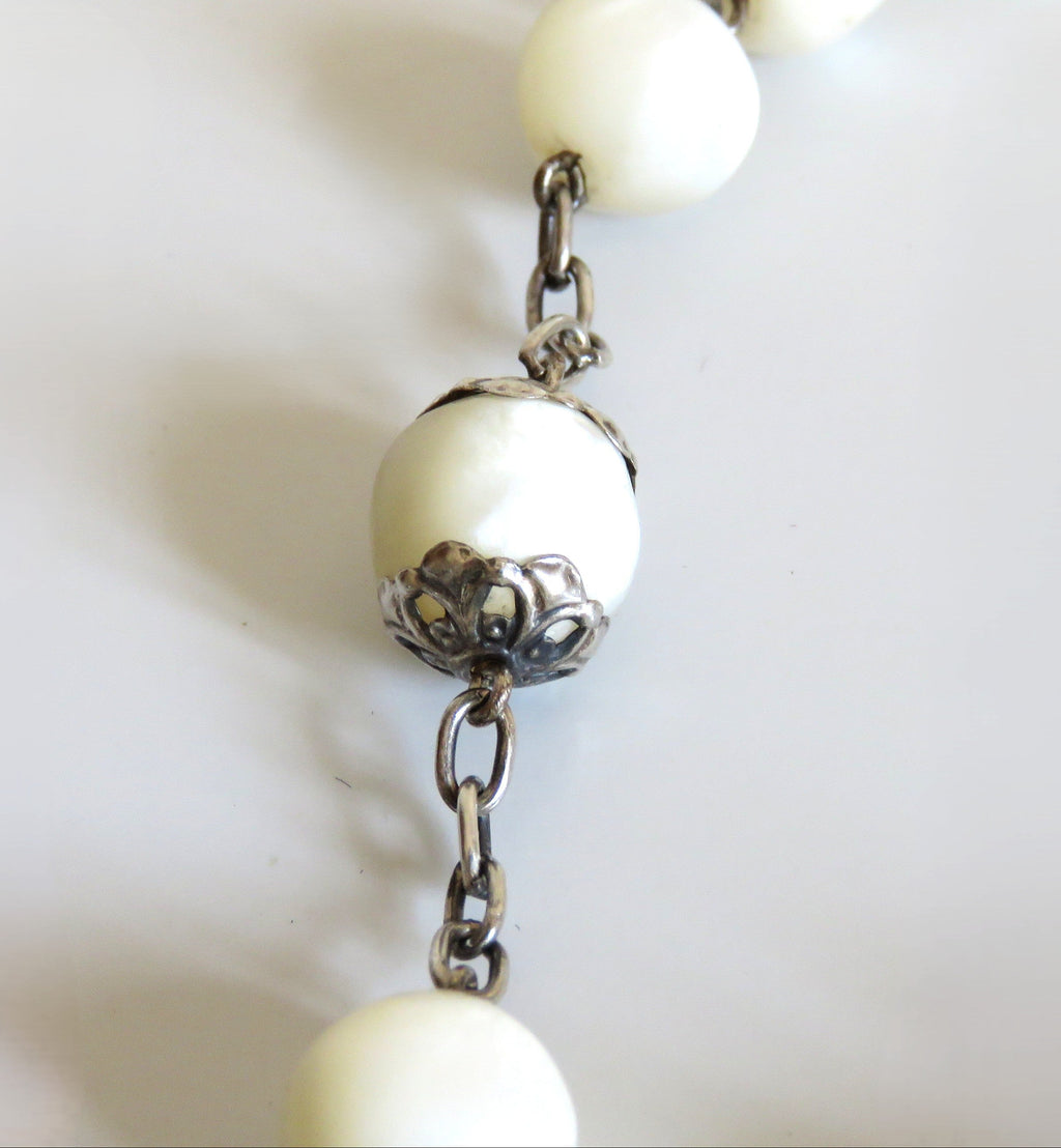 Pearl necklace with silver chain on a light background