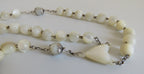 White rosary with a mouther of pearl heart on a white background