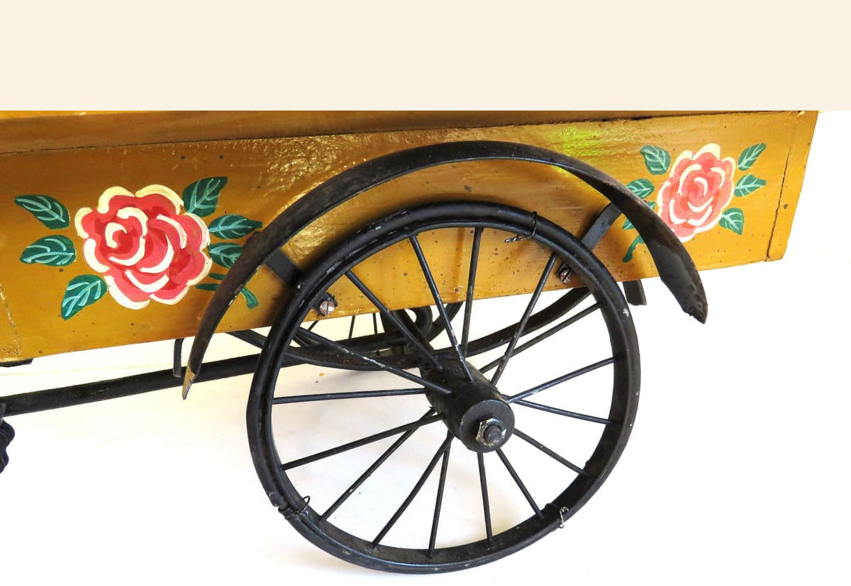 Wooden cart with floral designs and a large wheel on a white background