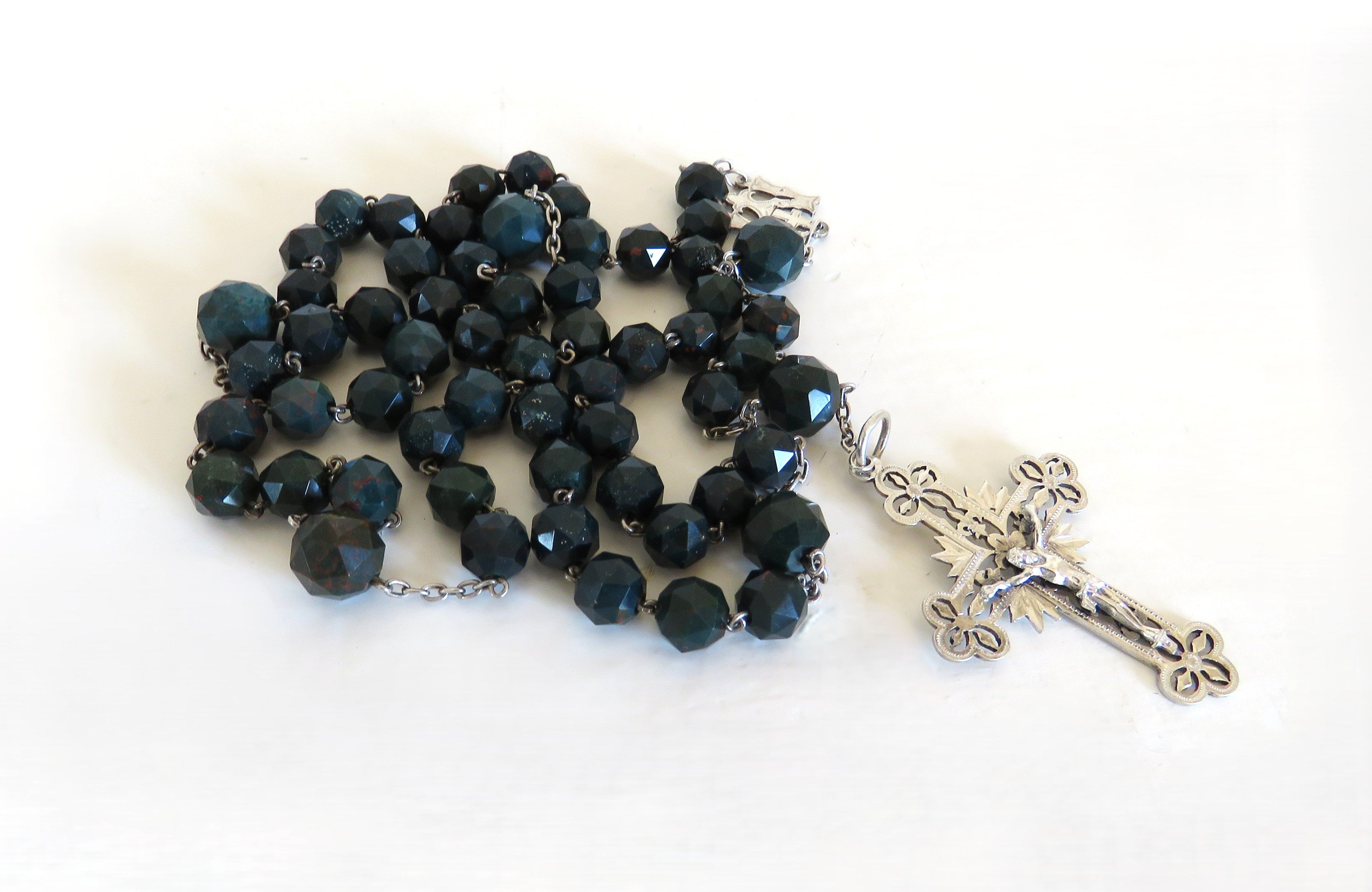 Bloodstone green rosary with a silver crucifix on a white background