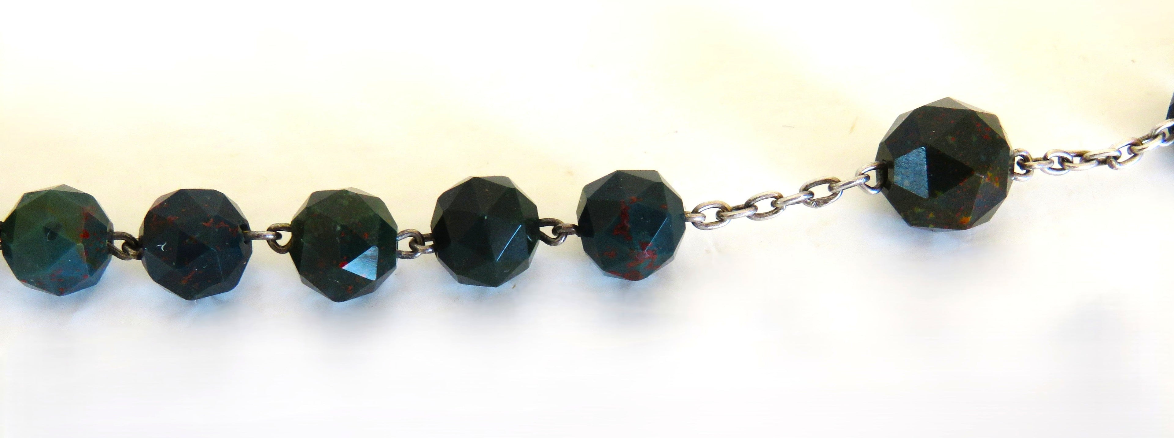 Beads on a Bloodstone green rosary with a silver crucifix on a white background
