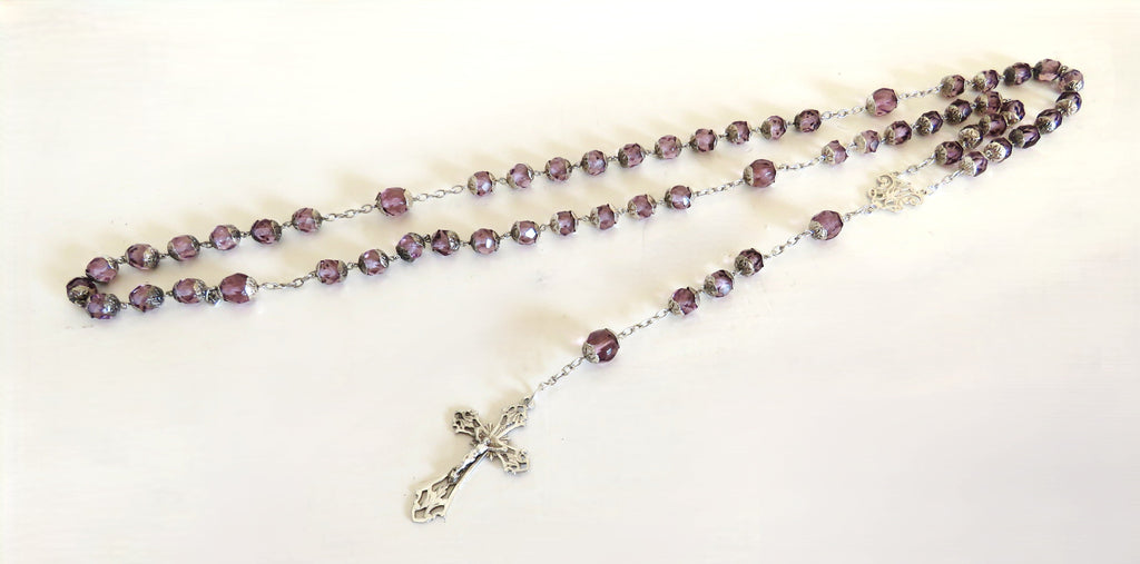 Purple and silver antique rosary on a white background
