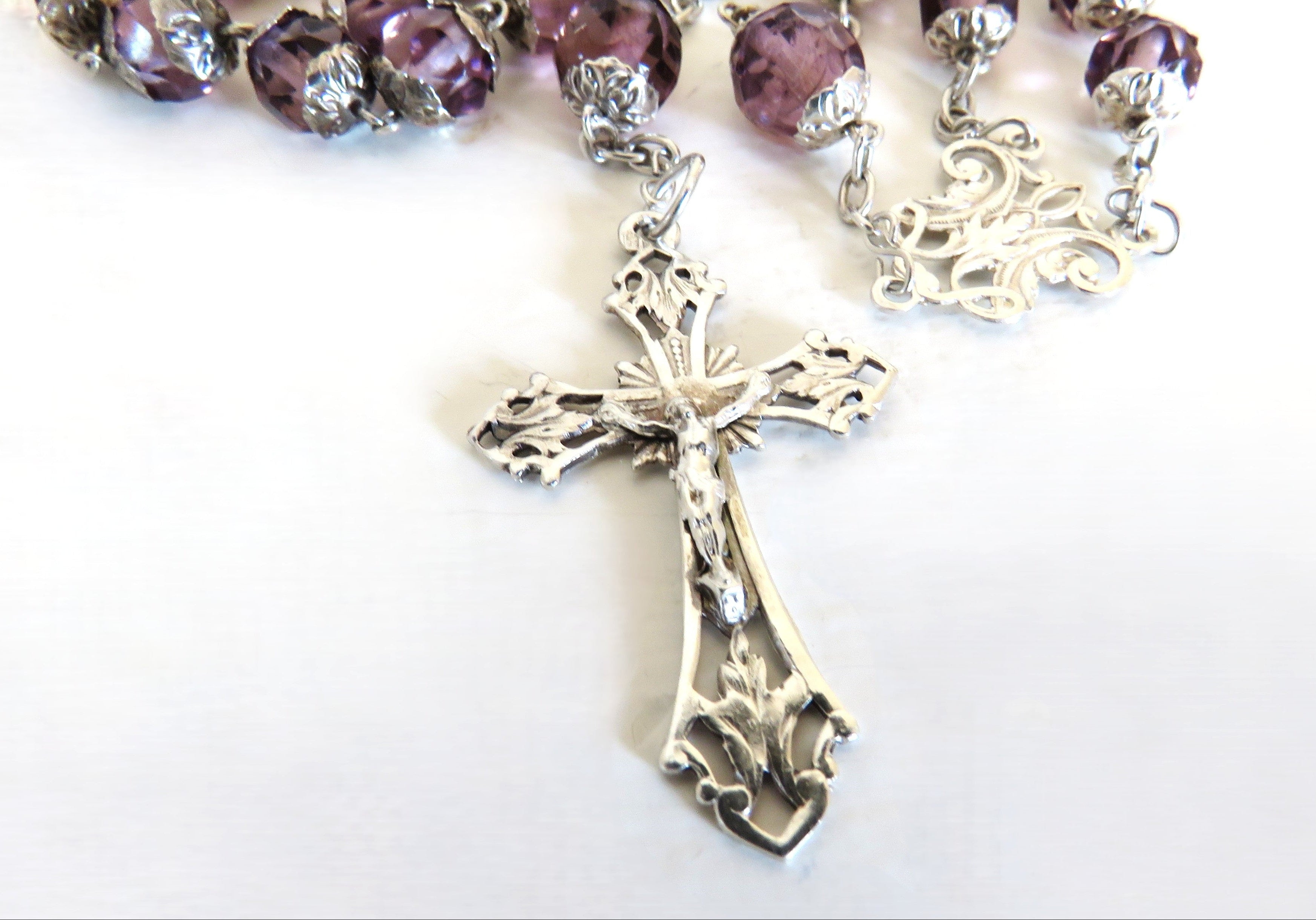 Silver rosary crucifix on a white background