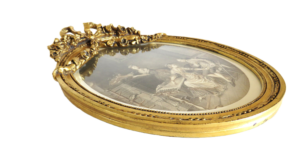 Decorative gold frame with a central oval mirror featuring classical scenes.