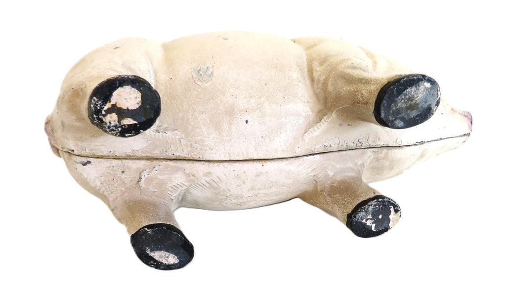 Under neath a white cast iron piggy bank on a white surface