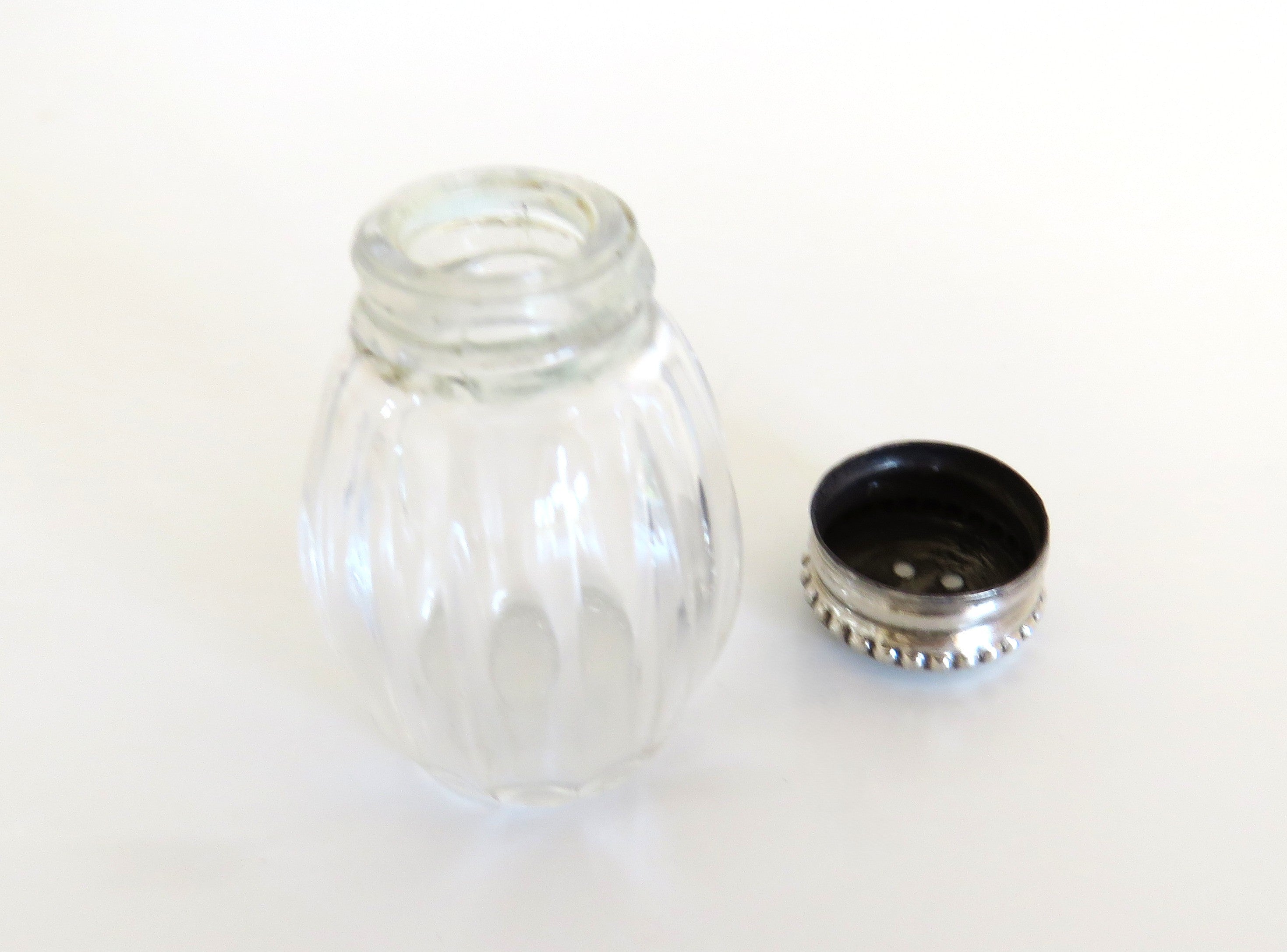 one silver and glass salt cellar with lid off on white background