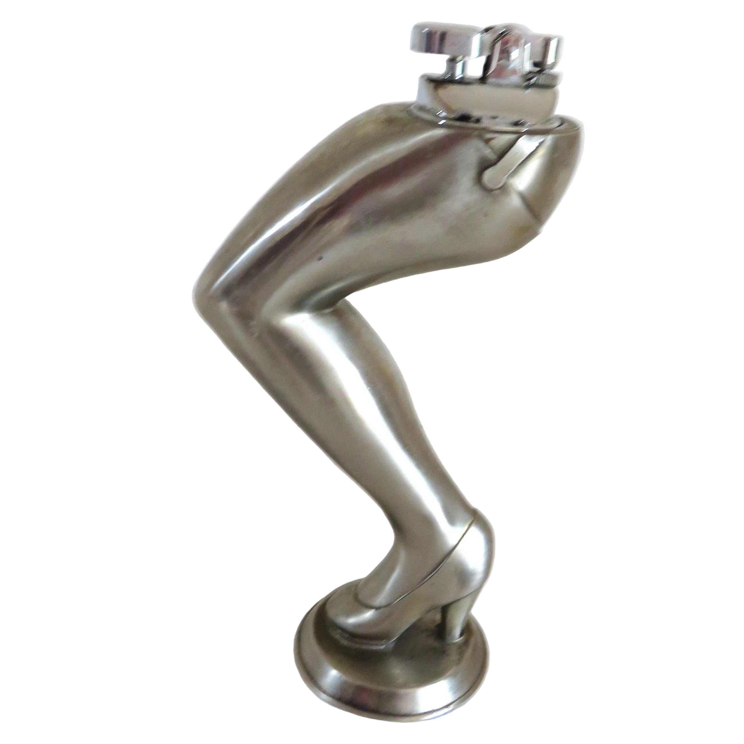 A cigarette lighter on a metallic silver sculpture of a bent leg wearing a high heel, standing on a round base against a plain white background.