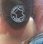 Close-up of a logo 'FABRICATION FRANCAISE'  resting on a beige surface.