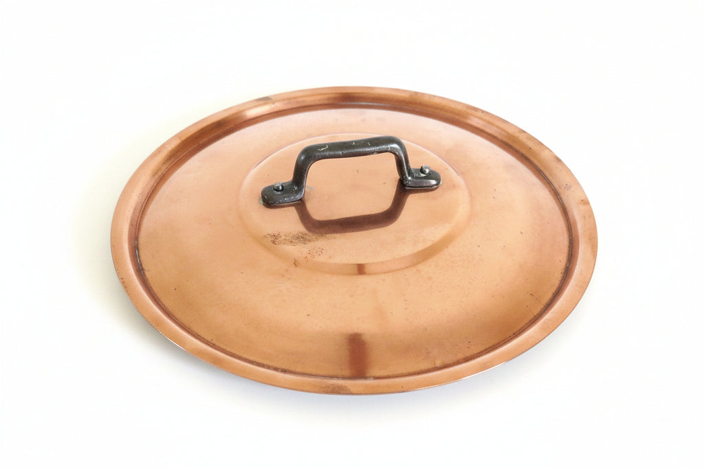 A round copper-colored metal lid with a black metal handle, shown on a white background.