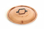 A round copper-colored metal lid with a black metal handle, shown on a white background.