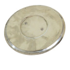 A round, metallic silver plate or shallow dish with a brushed finish, displayed on a white wooden surface.