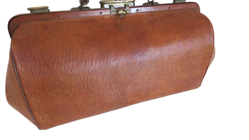 A vintage brown leather medical-style case with a textured epi leather finish, brass hardware, and a curved rectangular shape, photographed on a white background.