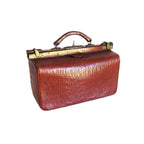 A vintage reddish-brown crocodile-embossed leather drs bag with a top handle and brass-tone clasp hardware, isolated on a white background.