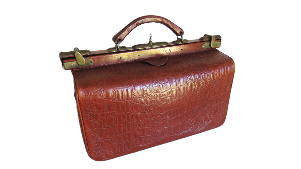 A vintage-style brown leather briefcase with an embossed crocodile pattern, brass handle, and brass clasp closure, isolated on a white background.