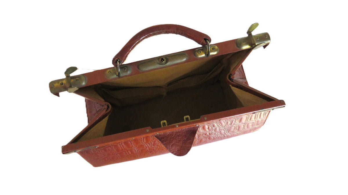 An open vintage brown leather briefcase or travel case with brass hardware, shown against a plain white background.