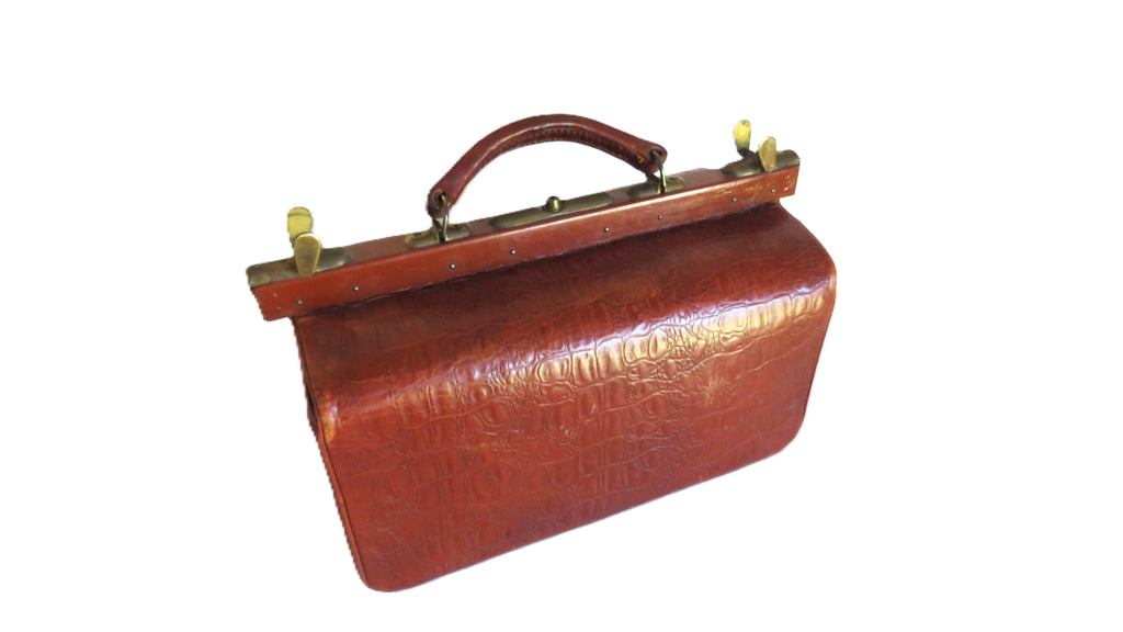 A vintage reddish-brown leather briefcase with a textured crocodile pattern, a top handle, and brass hardware on a white background.