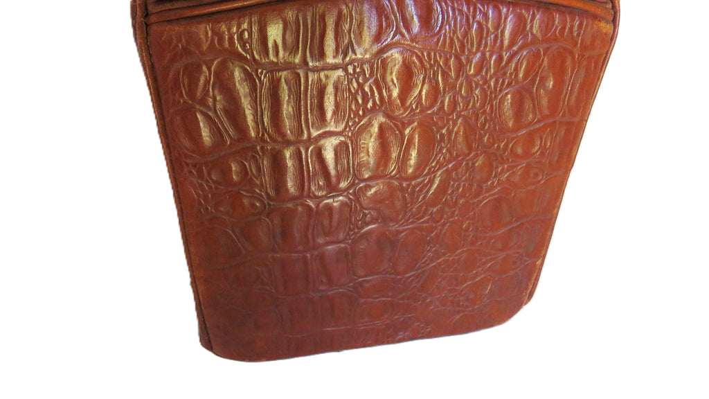 A close-up of a brown crocodile-embossed leather material, showing a glossy textured pattern on a plain white background.