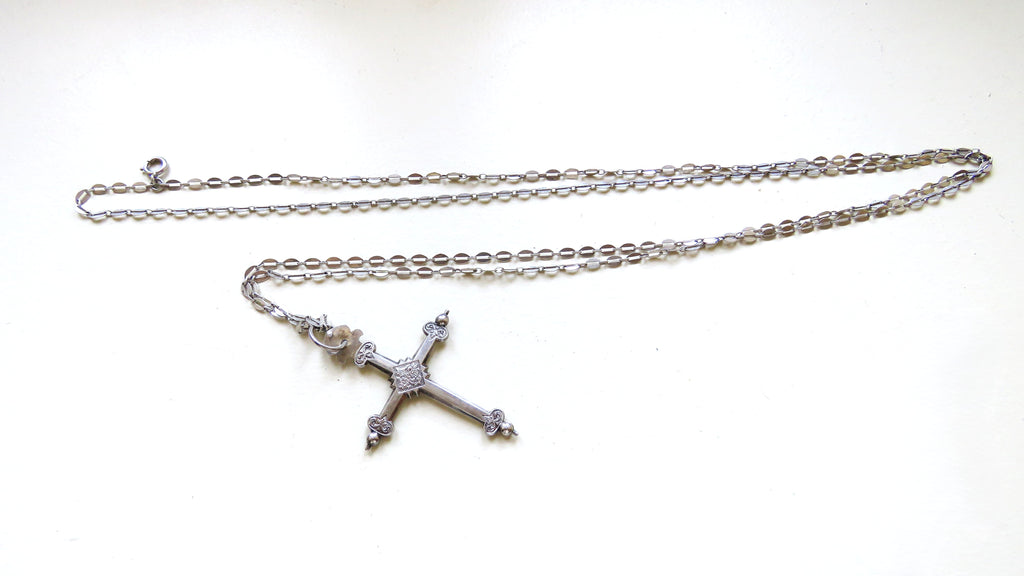 silver cross and chain on white background
