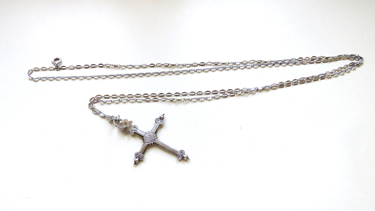 silver cross and chain on white background
