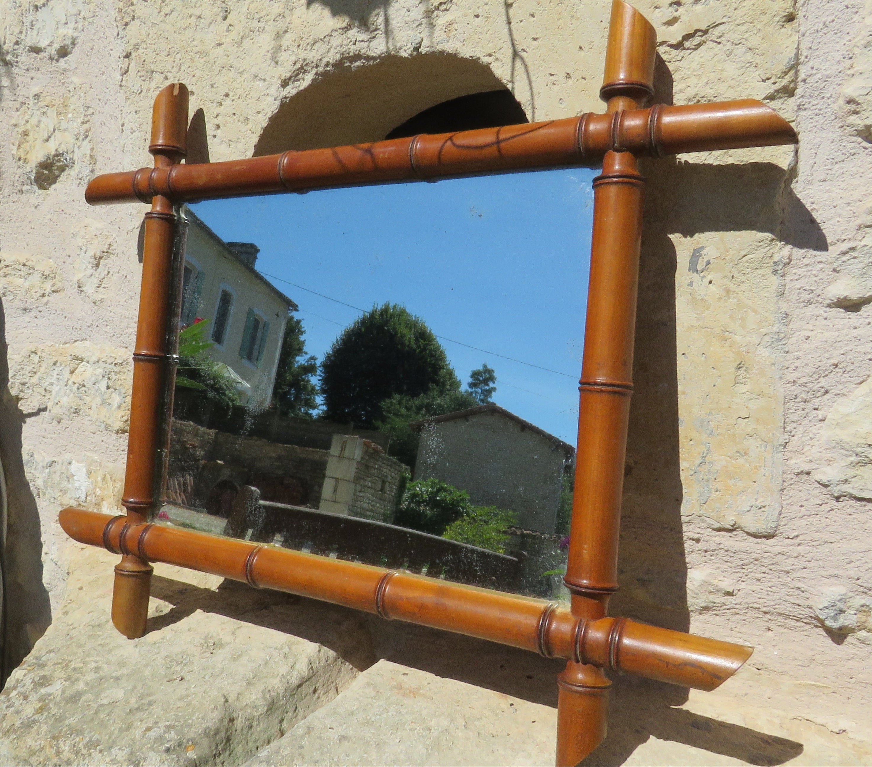 Decorative mirror with bamboo-style frame on a stone wall