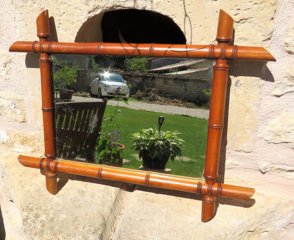 Decorative mirror with a bamboo-style frame on a stone wall