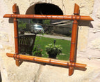 Decorative mirror with a bamboo-style frame on a stone wall