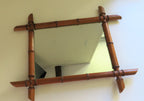 Decorative mirror with a bamboo-style frame on a white wall.