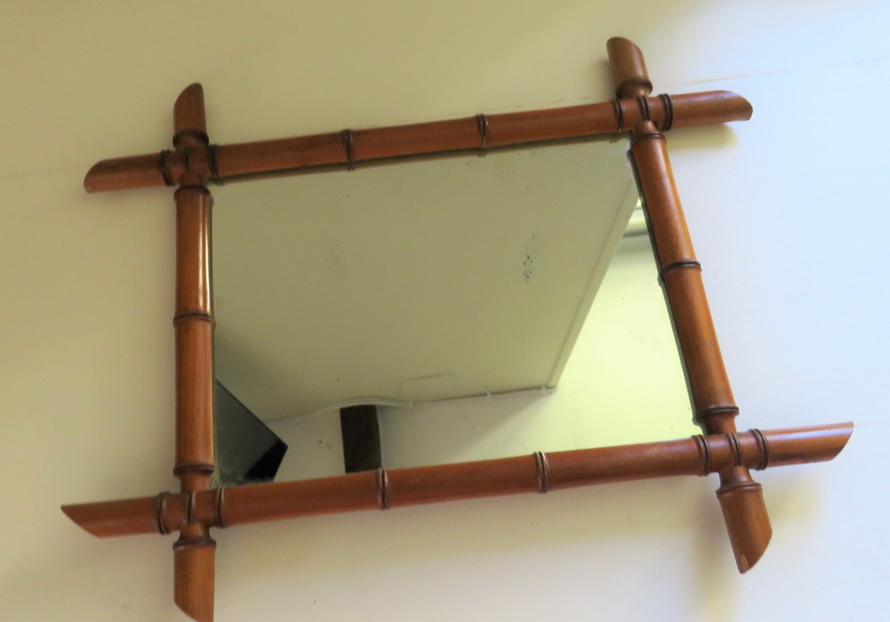 Decorative mirror with a bamboo-style frame on a white wall.