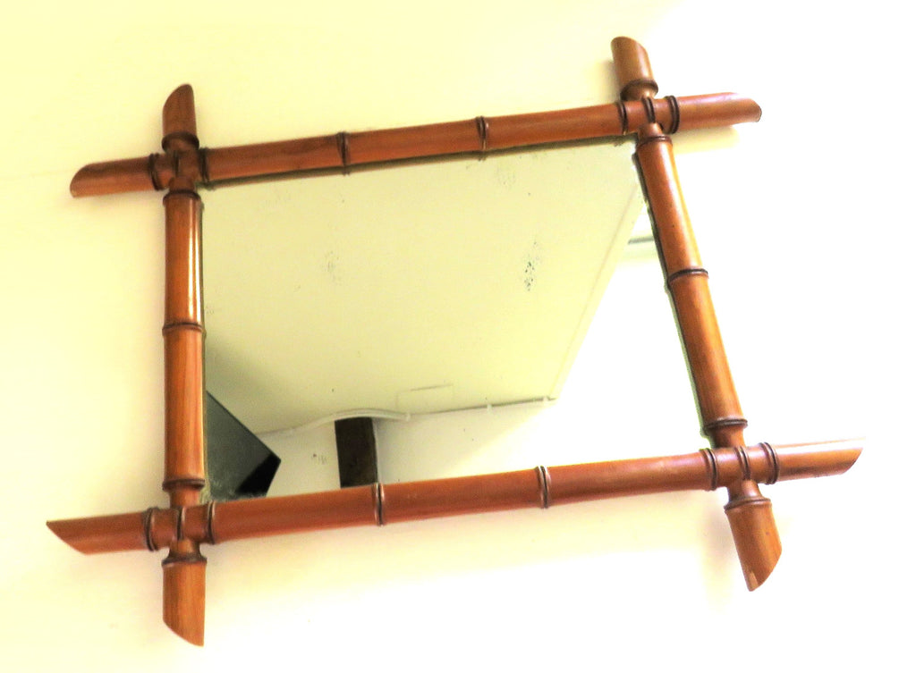 Rectangular mirror with a bamboo-style wooden frame on a white wall.