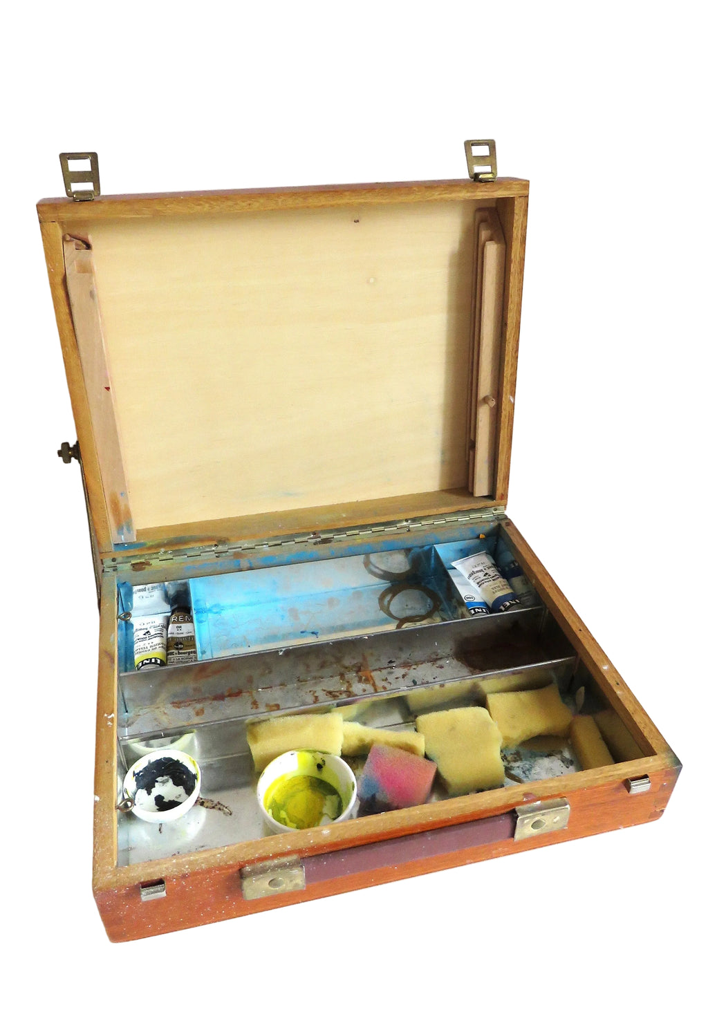 An open wooden artist's palette case with metal tools and paint containers inside, shown against a plain white background.